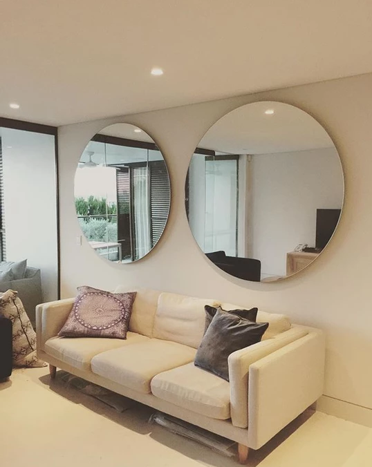 Large round mirrors mounted above a sofa